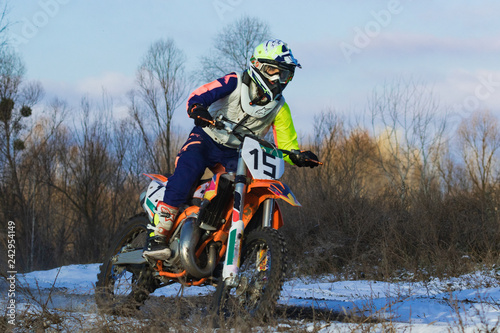 KYIV, Ukraine - November 28, 2018. Against the blue sky, a motorcycle racer rushes along a snowy dirt road. Active extreme rest.