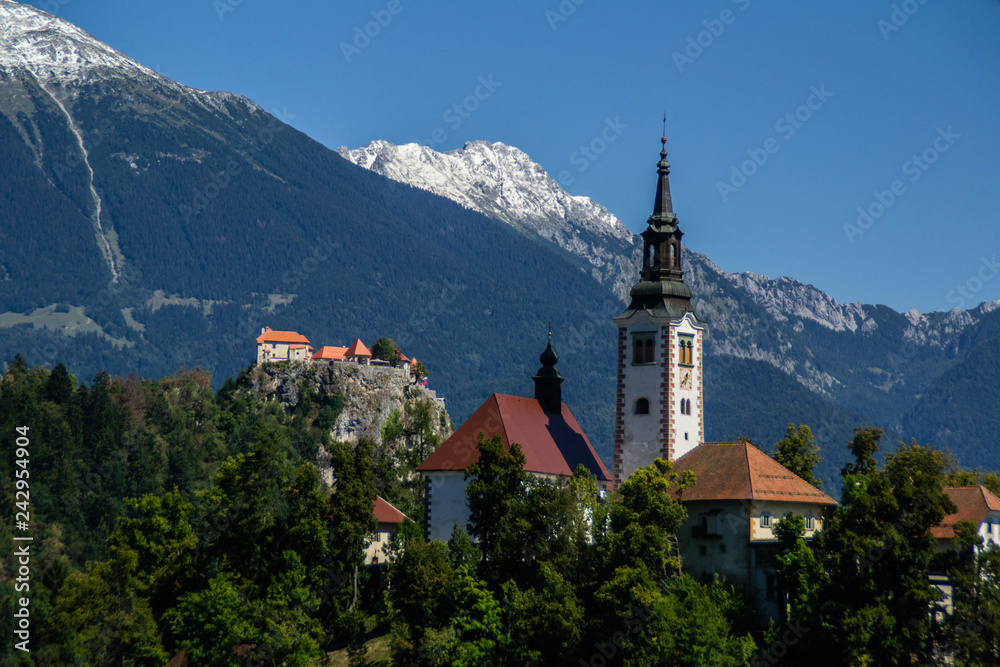Iconic landscape view of beautiful  St. Marys Church of Assumption on small island,lake Bled in Slovenia .Bled Castle on background. Summer scene travel Slovenia concept. Tourist popular attraction
