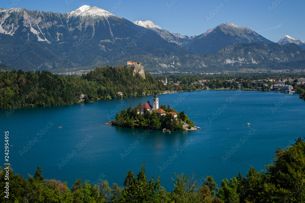 Iconic landscape view of beautiful  St. Marys Church of Assumption on small island,lake Bled in Slovenia .Bled Castle on background. Summer scene travel Slovenia concept. Tourist popular attraction