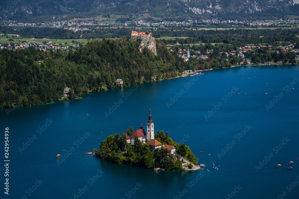 Iconic landscape view of beautiful  St. Marys Church of Assumption on small island,lake Bled in Slovenia .Bled Castle on background. Summer scene travel Slovenia concept. Tourist popular attraction