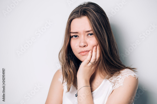 Beautiful sad unhappy woman feel pain on her teeth isolated on white background