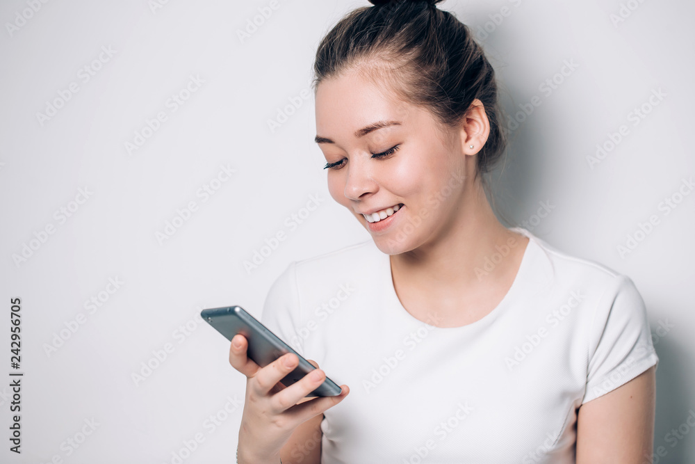 Happy young brunette woman smiling and using smartphone on white background Happy young brunette woman smiling and using smartphone on white background