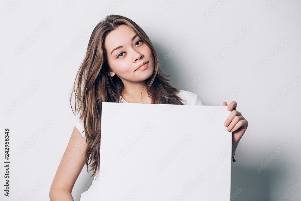 young smiling woman holding a blank sheet of paper for advertising, close-up young smiling woman holding a blank sheet of paper for advertising, close-up