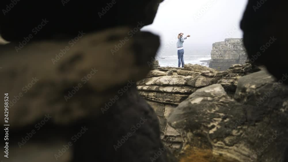 Young woman with outstretched arms walking on rough stony coast and admiring view of wonderful sea on foggy morning. in Portugal Young woman with outstretched arms walking on rough stony coast and admiring view of wonderful sea on foggy morning. in Portugal