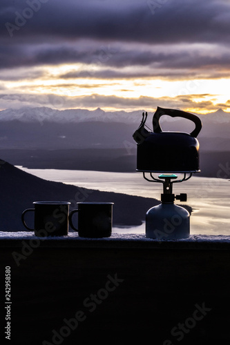 Outdoor cooking equipment or coffee making concept. Scenic landscape view of small mugs and kettle/pot standing on gas stove. Beautiful morning scene up in the Fiordland National Park, New Zealand