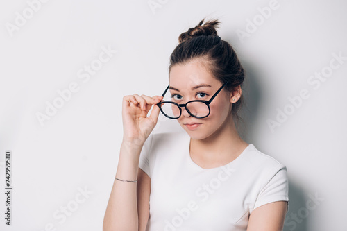 Pretty woman with round glasses looking at the camera on white background.