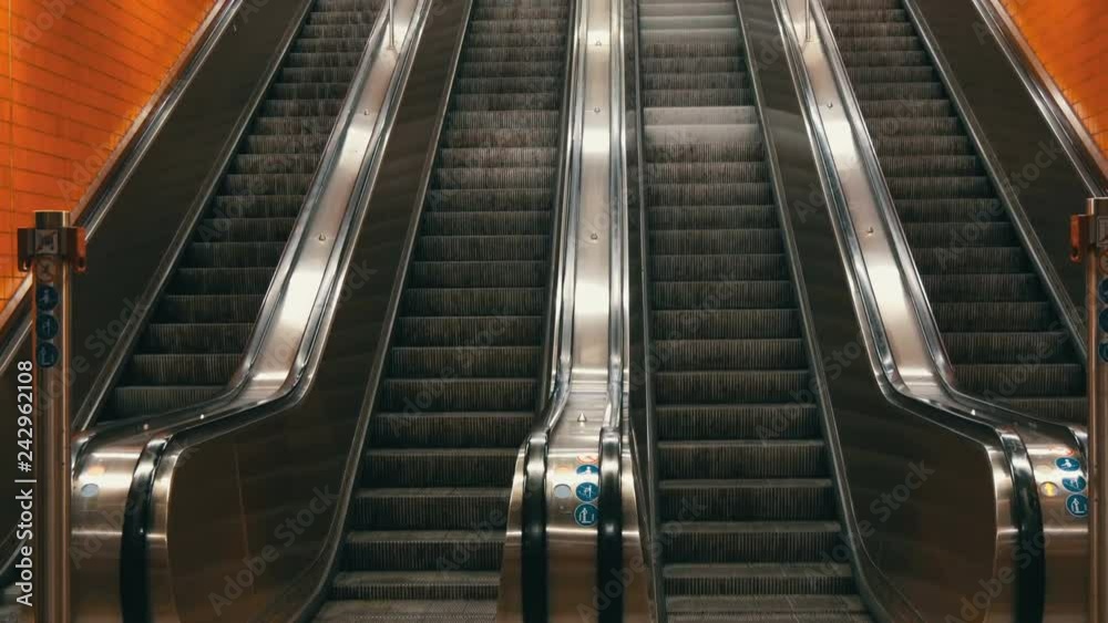 Large modern escalator in subway. Deserted escalator without people on four lanes that move up and down Large modern escalator in subway. Deserted escalator without people on four lanes that move up and down