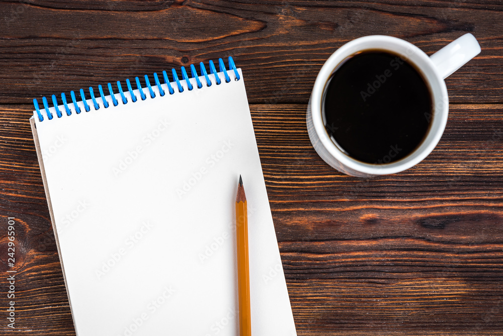 Notepad with yellow pencil and coffee on wooden background. Goals for the new year. Planning and schedule concept. To do list. Notepad with yellow pencil and coffee on wooden background. Goals for the new year. Planning and schedule concept. To do list.