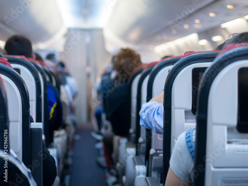 Passenger aircraft cabin with passengers on board. Blurred background.