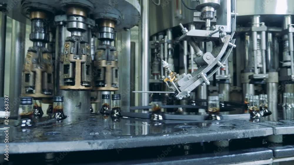 Caps are getting bound to glass bottles while moving along the conveyor