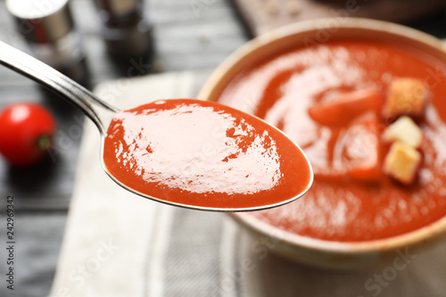 Obraz na plátně Spoon with fresh homemade tomato soup on blurred background, closeup