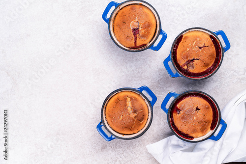 homemade dessert with berries in individual servings in blue pan on a light marble backdrop