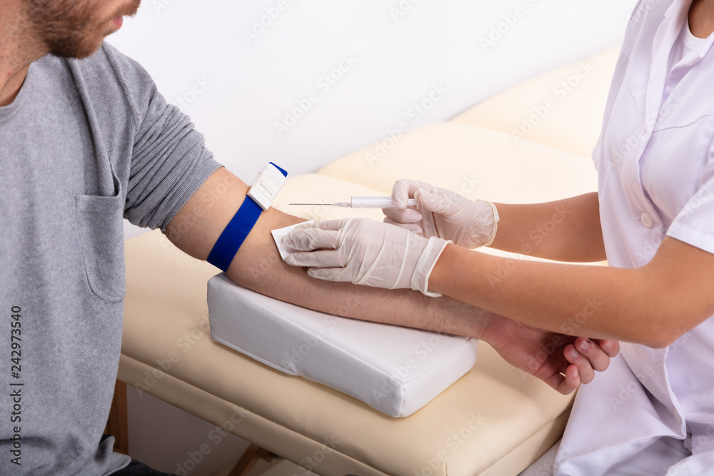 Fototapeta premium Doctor Injecting Patient With Syringe To Collect Blood