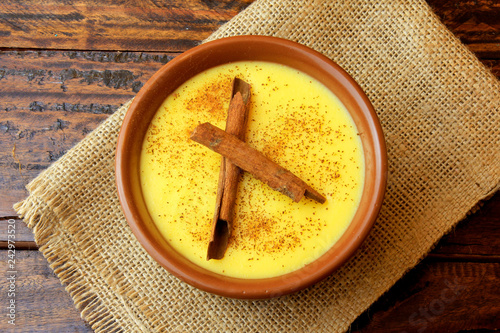 Curau, cream of corn sweet and dessert typical of the Brazilian cuisine, with cinnamon placed in ceramic bowl on wooden table. Top view