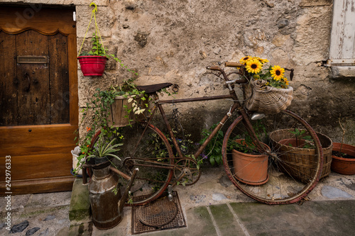 Old bicycle with flowers in the medieval town of Entreveux, France photo