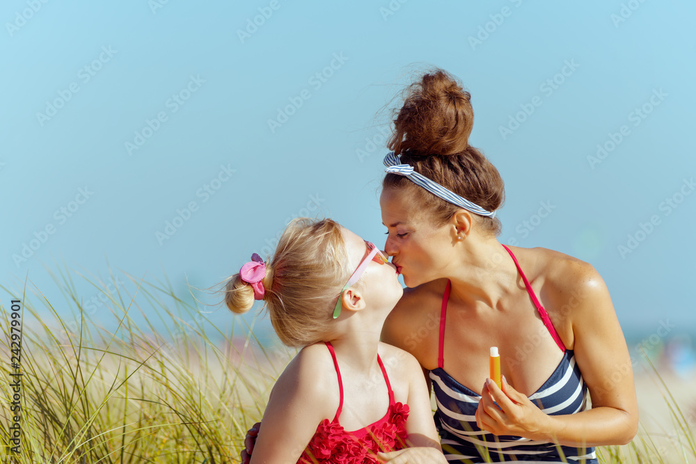 smiling mother and child holding lipstick with spf and kissing smiling mother and child holding lipstick with spf and kissing