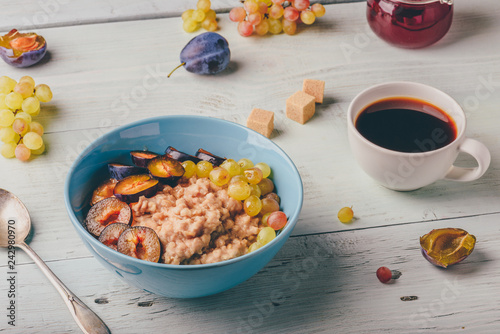 Porridge with plum, grapes and cup of coffee photo