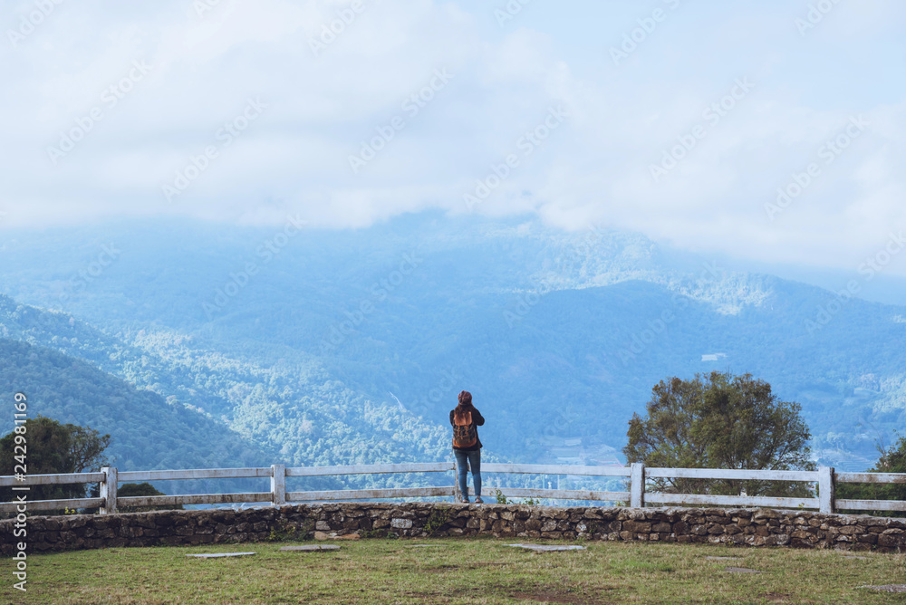 Naklejka premium Happy Asian women Travel relax Standing at the view point Look at the watching the nature View of mountains the mist beautiful at sheep farm Doi Inthanon.