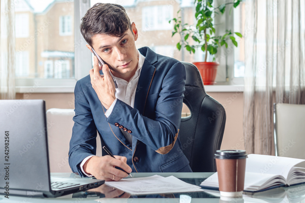 Businessman sitting at the table signing documents in the office. Concept of transactions and work with securities Businessman sitting at the table signing documents in the office. Concept of transactions and work with securities