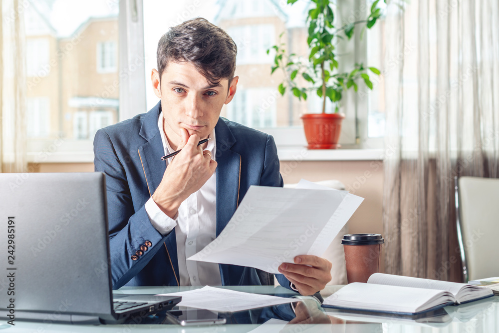 Male lawyer sitting at a work place examing documents. Concept of the office working with documents Male lawyer sitting at a work place examing documents. Concept of the office working with documents