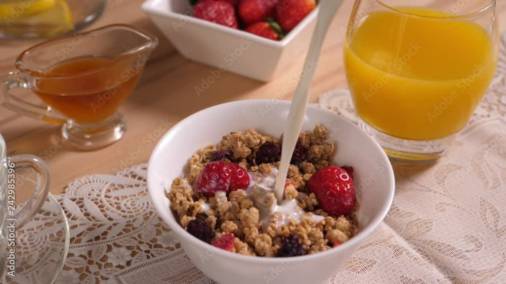 Milk pours into a cup of muesli with berries Milk pours into a cup of muesli with berries