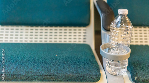 Bench at a International Airport with a water bottle in the bottle holder. photo