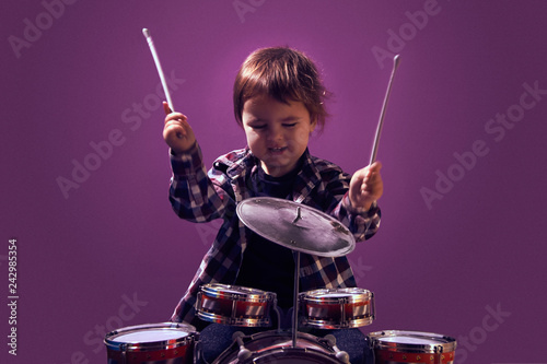Happy young child playing drums color background