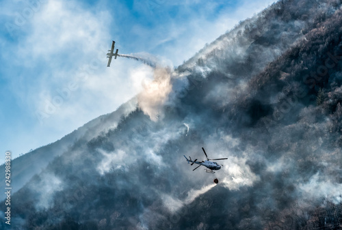 Firefighting Aircraft and Helicopter dropping the water for fighting a fire on mountain, above Lake Ghirla in Valganna, province of Varese, Italy photo