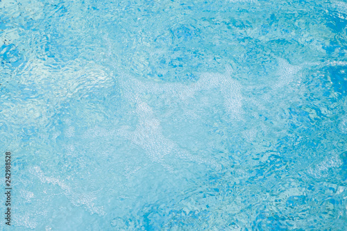 Ripple water in swimming pool sun reflection, blue background.