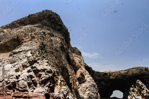 Several birds flying over a rock formation on the Ballestas Islands (Paracas, Peru)