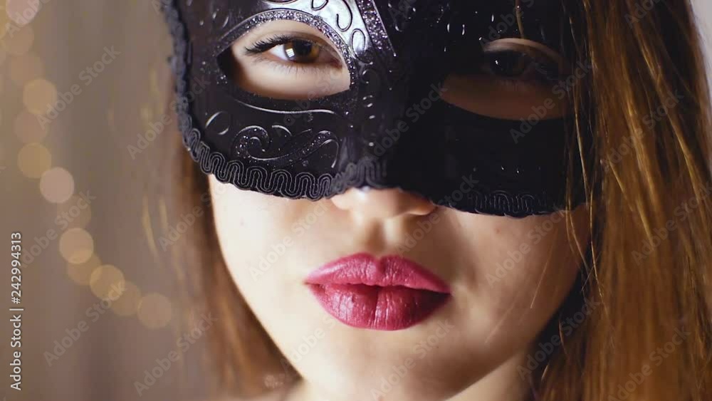 A brown-haired girl in a black mask looks into the camera A brown-haired girl in a black mask looks into the camera
