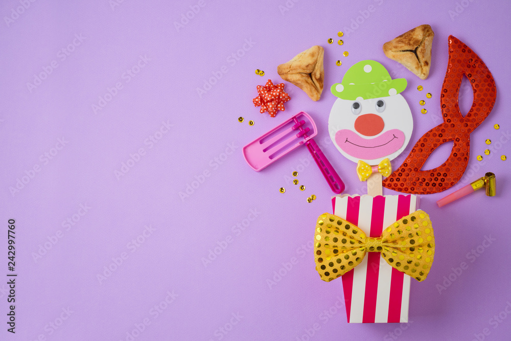 Jewish holiday Purim background with carnival mask, paper clown and hamantaschen cookies.