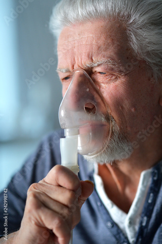 Portrait of sick senior man with inhaler 
