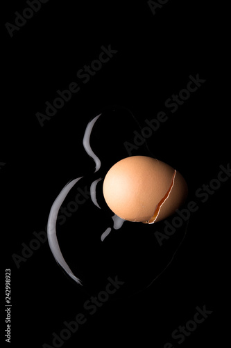 A cracked egg spills the clear albumen on to a black background.