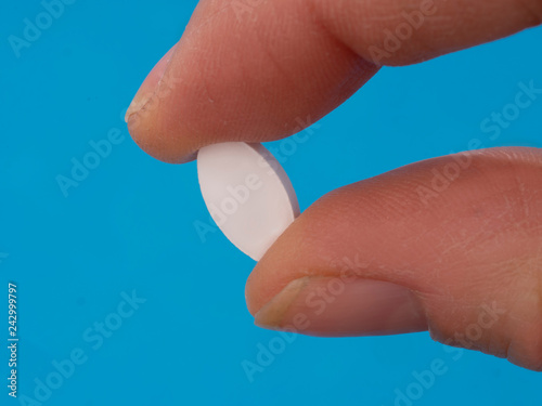 Alendronate sodium tablet between fingers  a nonhormonal medication for treating postmenopausal osteoporosis in women.