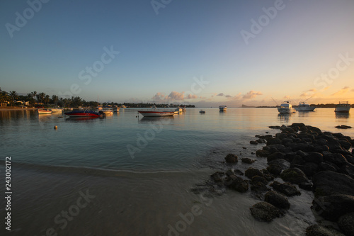 Sunset on the beach of the island of Mauritius where yachts float on water and boats © kazanovskyiphoto