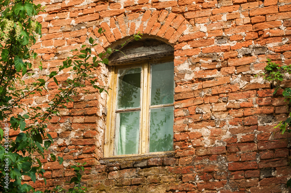 Grunge broken window of old rural weathered neglected abandoned house red brick wall closeup Grunge broken window of old rural weathered neglected abandoned house red brick wall closeup