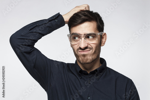 Young thoughtful business man thinking, scratching his head trying to find solution