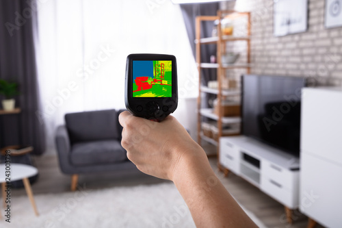 Woman Using Infrared Thermal Camera In Living Room