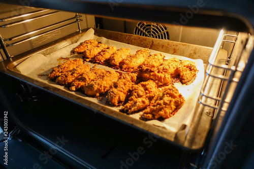 Freshly baked chicken fillet on a baking sheet in an electric oven. Cooking chicken nuggets. Series.