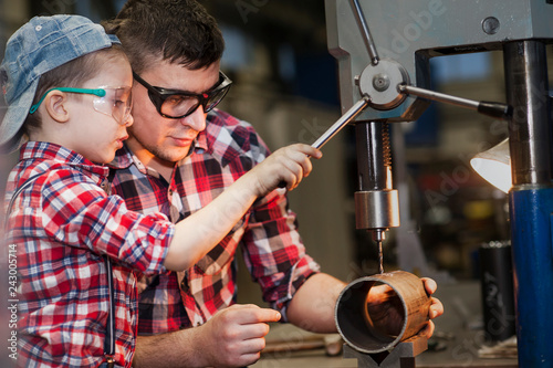 good father took his little son to work with metal. Concept of relationship, child at work turner