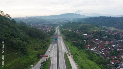 Semarang, Central Java / Indonesia - January 11, 2019: Aerial scenery of Trans-Java Toll Road with residential houses and tropical hills background. Shot in 4k resolution photo