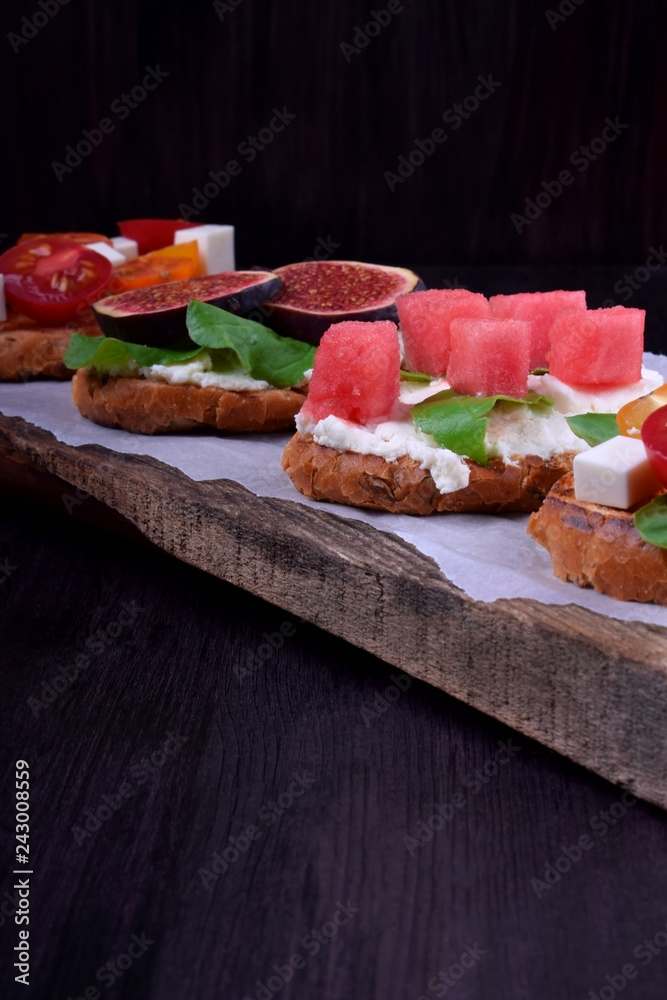 Assortment of bruschettas with figs, watermelon, cherry tomatoes, cheese and honey Assortment of bruschettas with figs, watermelon, cherry tomatoes, cheese and honey