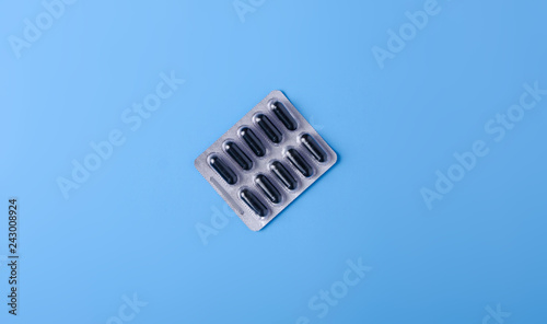 Blister black capsule on blue background, top view, medical pharmacy concept