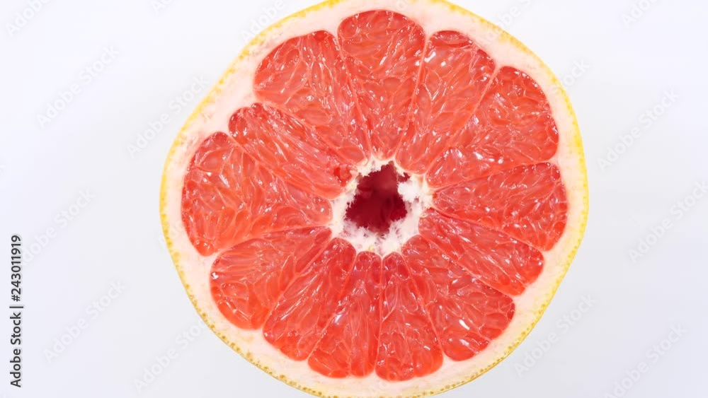 Fresh half of grapefruit citrus fruit on plate rotating. Healthy eating, weight loss, light meal. Top view Fresh half of grapefruit citrus fruit on plate rotating. Healthy eating, weight loss, light meal. Top view