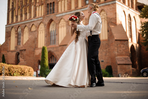Happy and beautiful married couple dancing in the background of vintage red brick building with