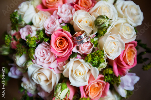 A pair of wedding rings on a bouquet of colorful flowers, close up shot © FrameSculptor