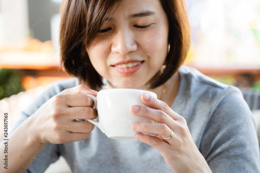 Asian woman hand closeup Holding a white coffee mug Smiling, happy Drinking black coffee during each meal will help to dissolve fat. Helps reduce blood cholesterol. Good health care concept Asian woman hand closeup Holding a white coffee mug Smiling, happy Drinking black coffee during each meal will help to dissolve fat. Helps reduce blood cholesterol. Good health care concept