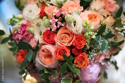 A pair of wedding gold rings on a bouquet of colorful flowers, close up shot