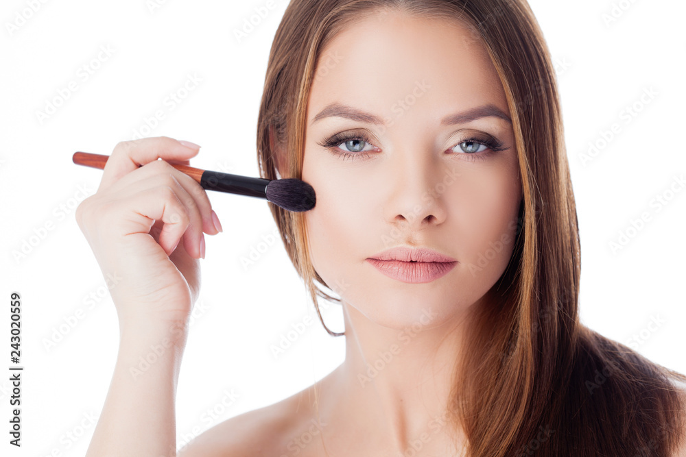 Use the powder. Attractive girl doing makeup. Portrait of a beautiful young woman using a brush for Foundation Use the powder. Attractive girl doing makeup. Portrait of a beautiful young woman using a brush for Foundation
